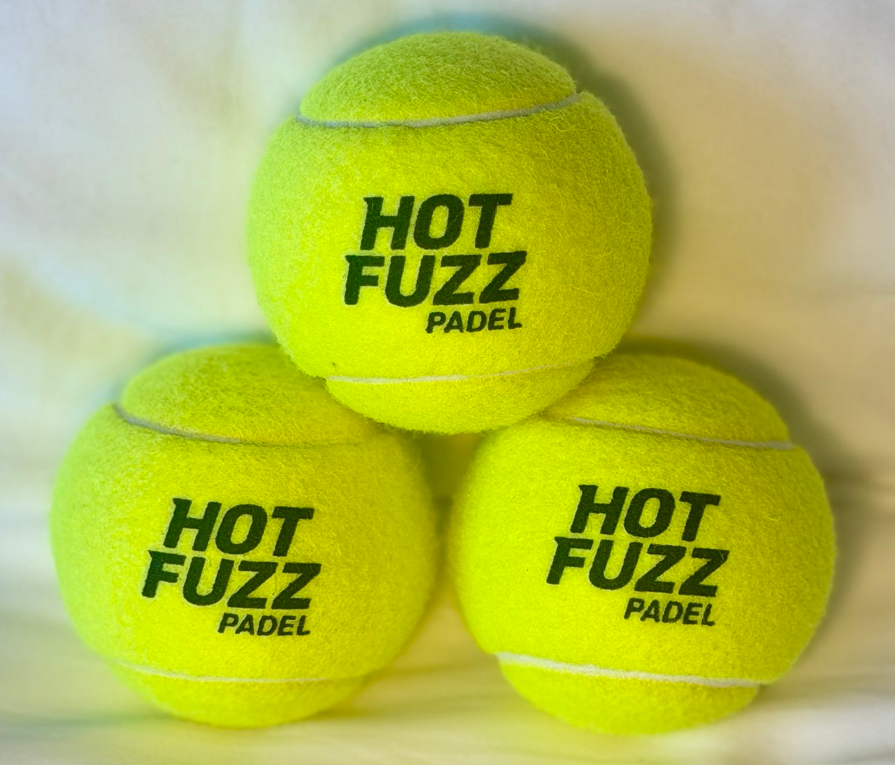 Three stacked Hot Fuzz Padel Balls